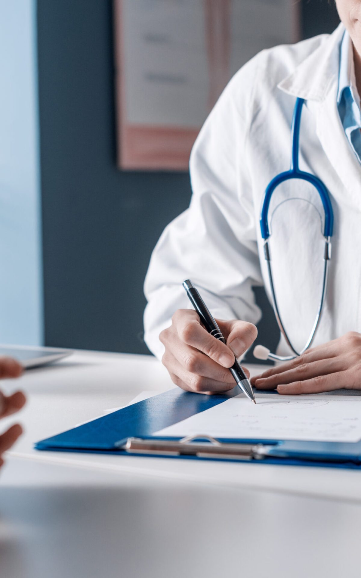 Doctor sitting at desk and writing a prescription for her patient